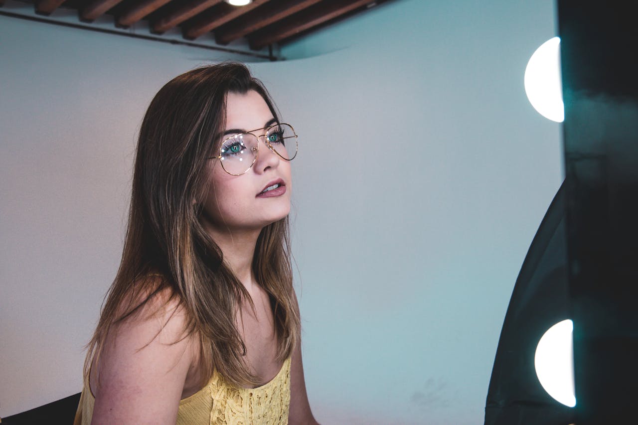 Portrait of a fashionable woman with glasses under studio lighting.